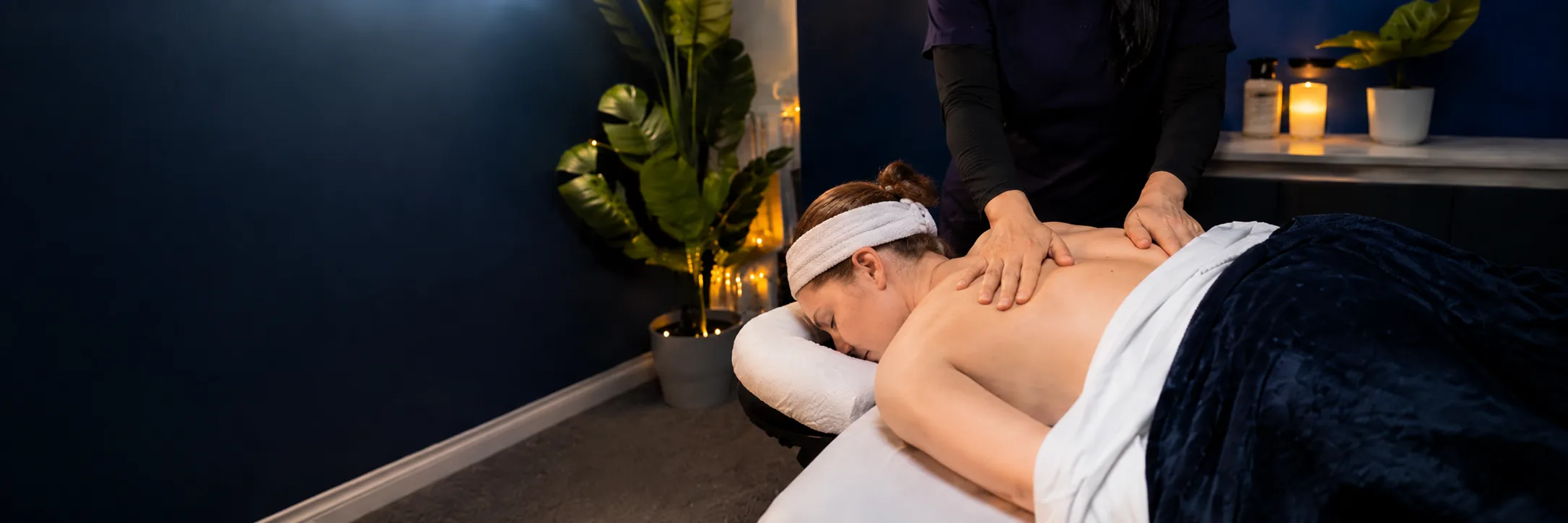 Massage treatment in progress, therapist's hands working on a client's shoulder and back in dark, moody light